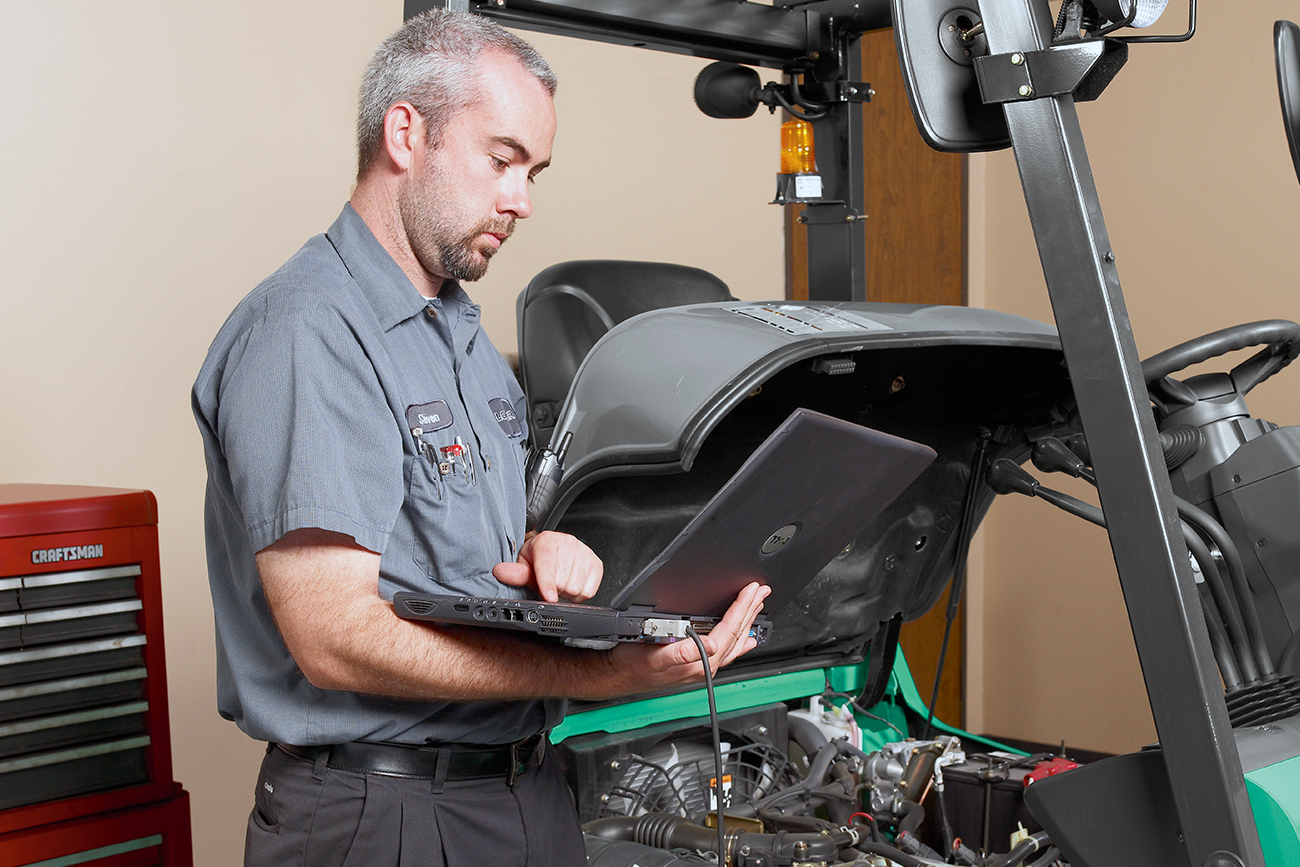 Forklift technician looking at laptop