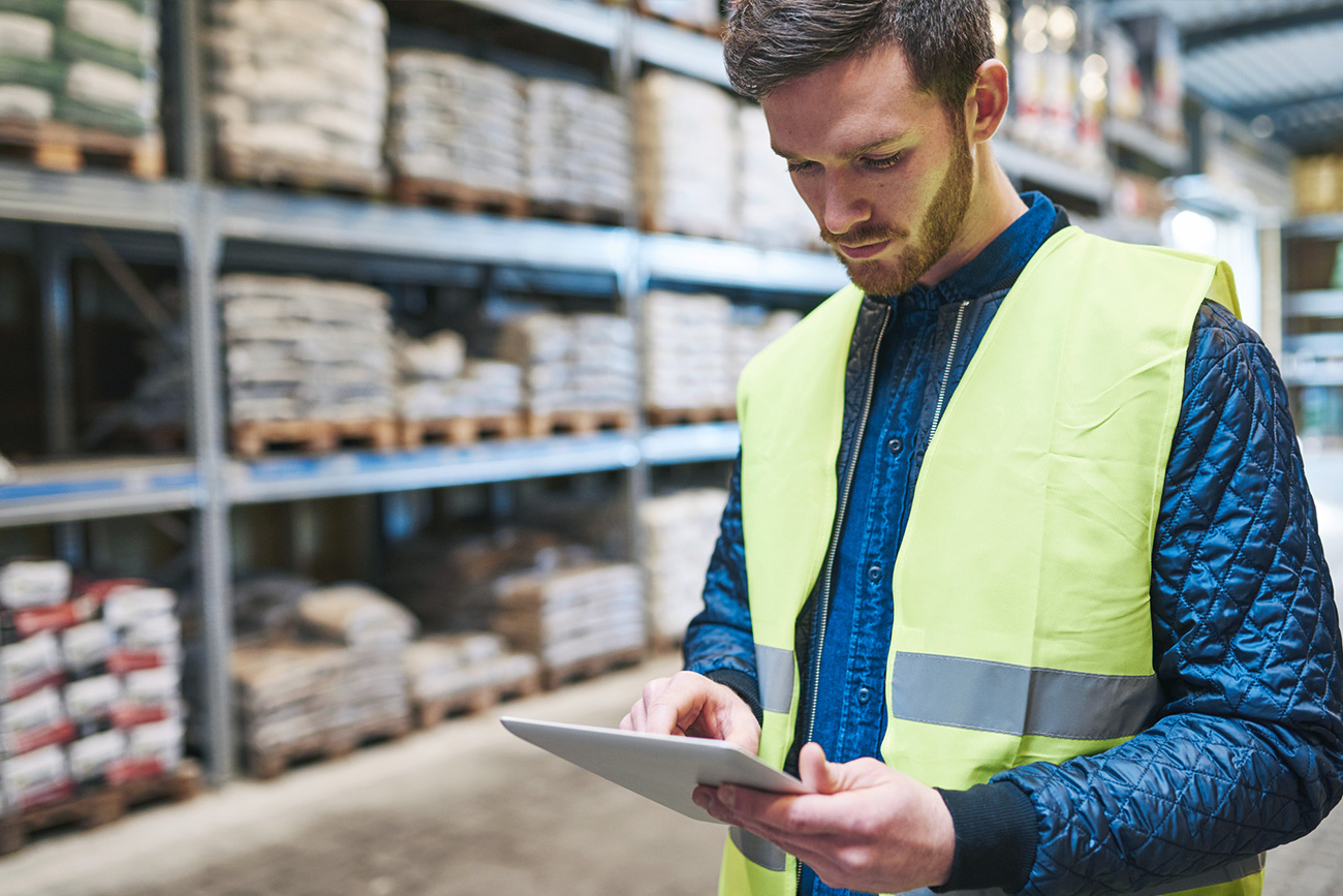 Man in warehouse looking at WMS on tablet