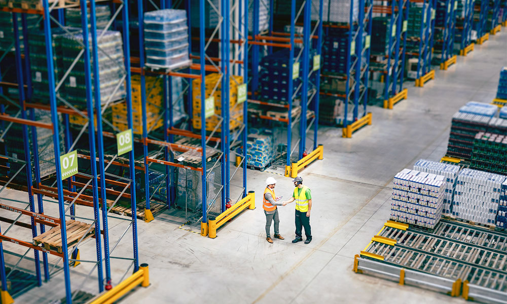 Two workers in warehouse by racking