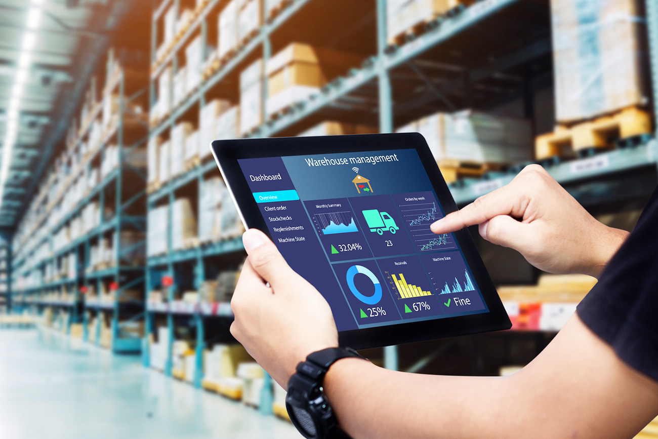 Person using a tablet with WMS in a warehouse aisle